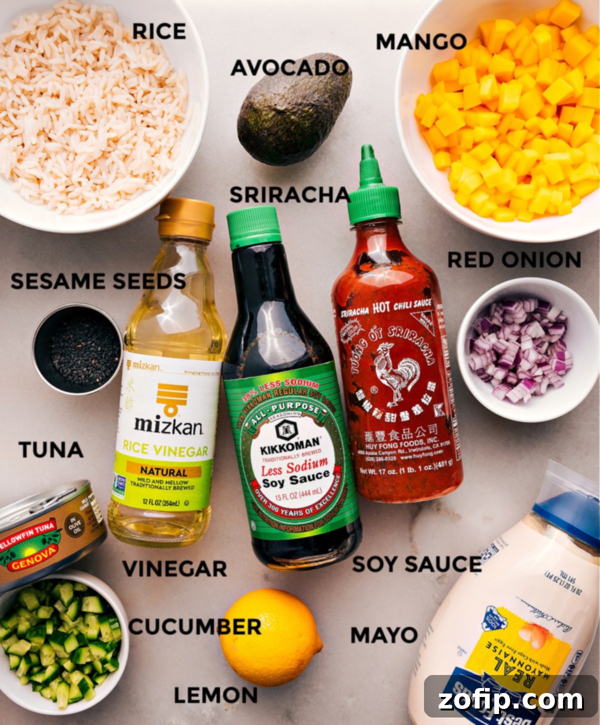 All the vibrant ingredients are prepped and ready for easy assembly: fresh mango, crisp cucumber, zesty red onion, rich avocado, savory tuna, fluffy rice, and flavorful sauces like soy sauce and sriracha mayo, alongside sesame seeds for garnish.