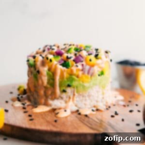 Beautifully stacked tuna sushi layers drizzled with spicy mayo and sesame seeds, ready to be enjoyed.