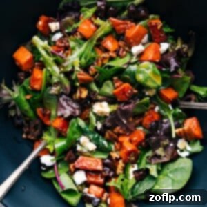 A vibrant bowl of sweet potato salad, featuring diced roasted sweet potatoes mixed with various colorful ingredients.