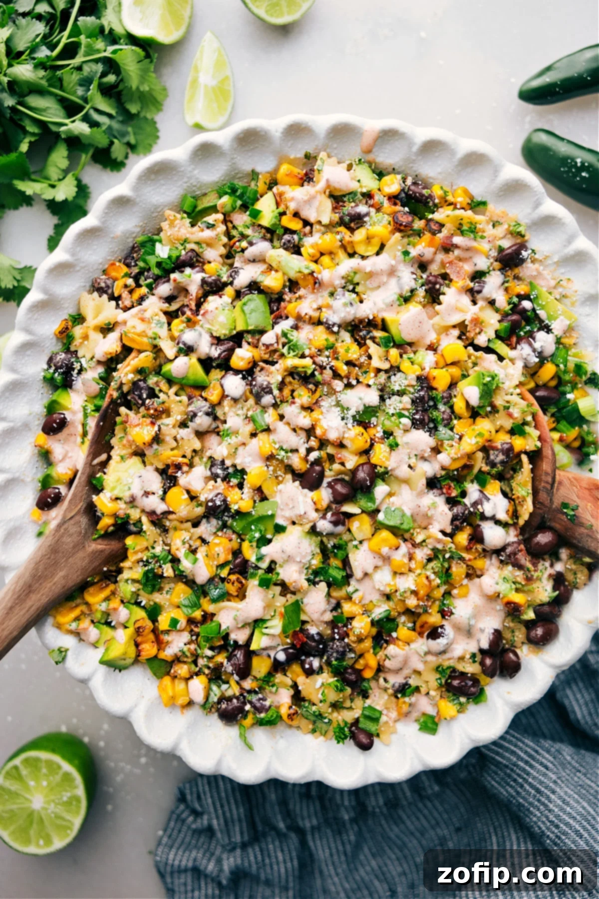 Delicious Mexican Street Corn Pasta Salad Ready to Enjoy A large bowl of Mexican Street Corn Pasta Salad, beautifully garnished with fresh cilantro and a lime wedge, ready to be served. The vibrant colors of corn, avocado, cilantro, and red peppers are enticing.