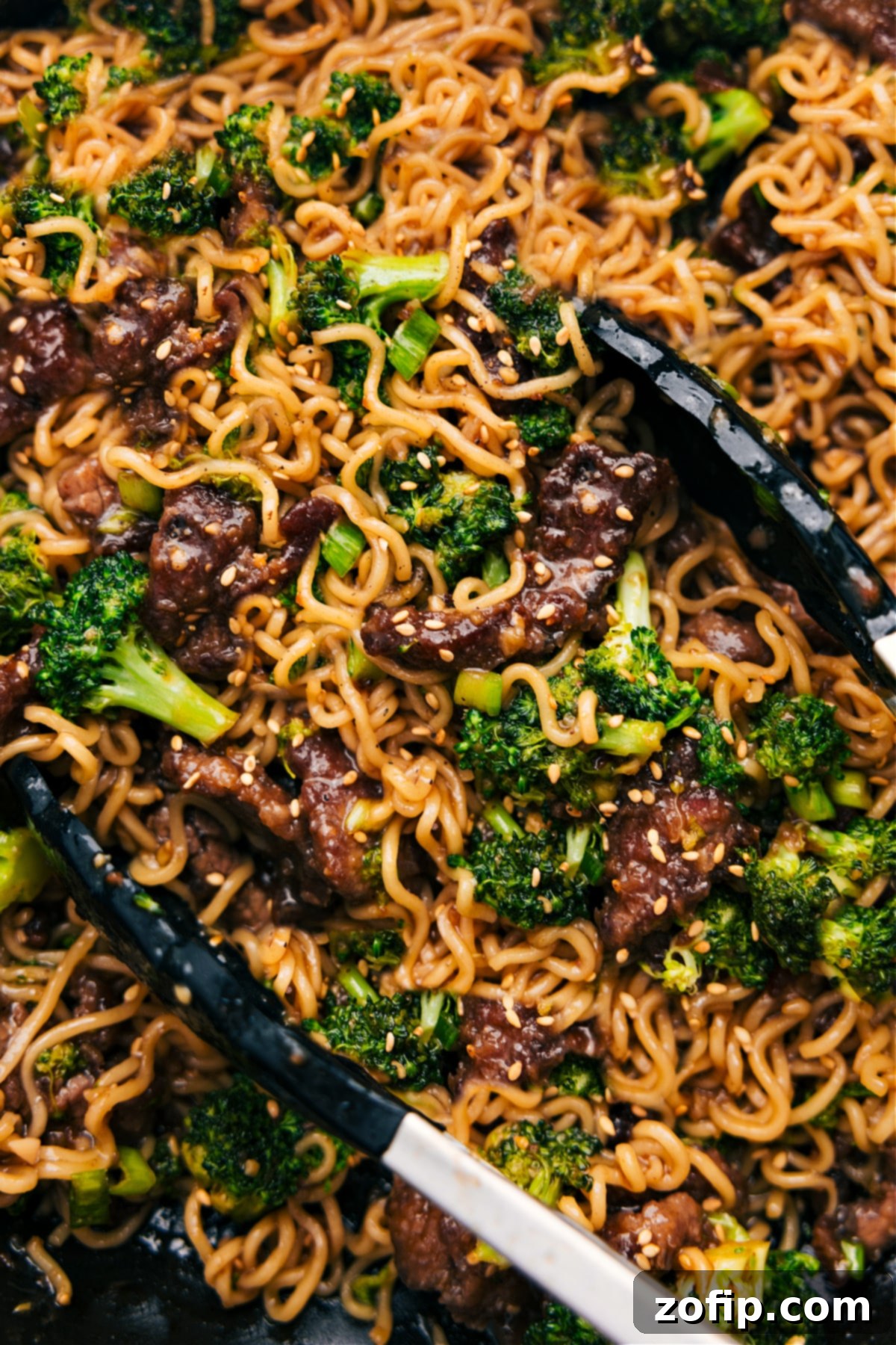 A beautifully presented bowl of Beef and Broccoli Ramen, garnished with fresh green onions and toasted sesame seeds, ready to be enjoyed.