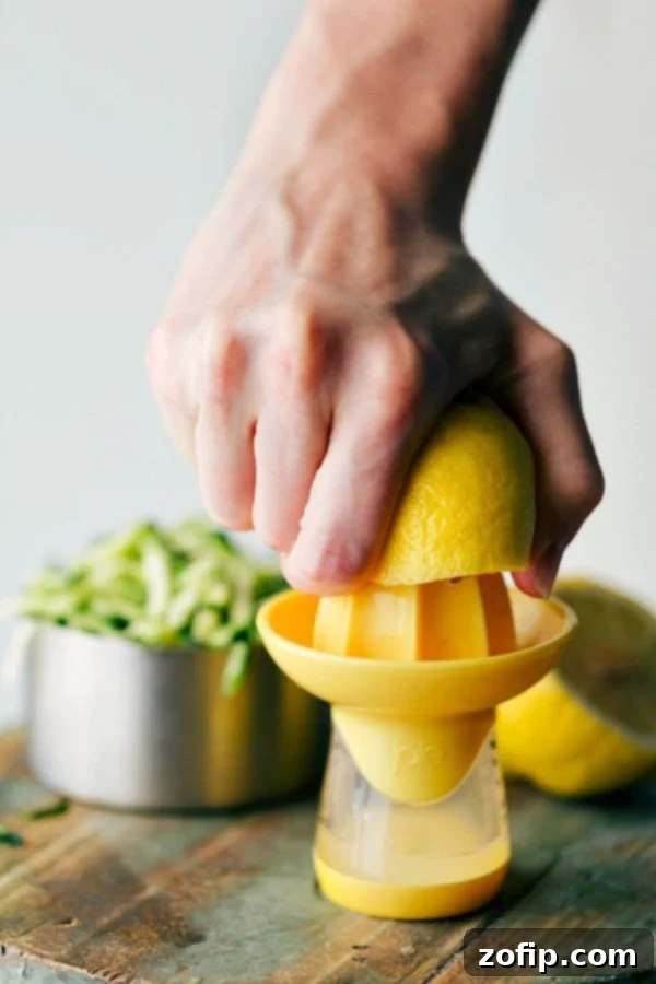 A fresh lemon being squeezed by hand to extract its juice, highlighting the key ingredient for a zesty flavor.