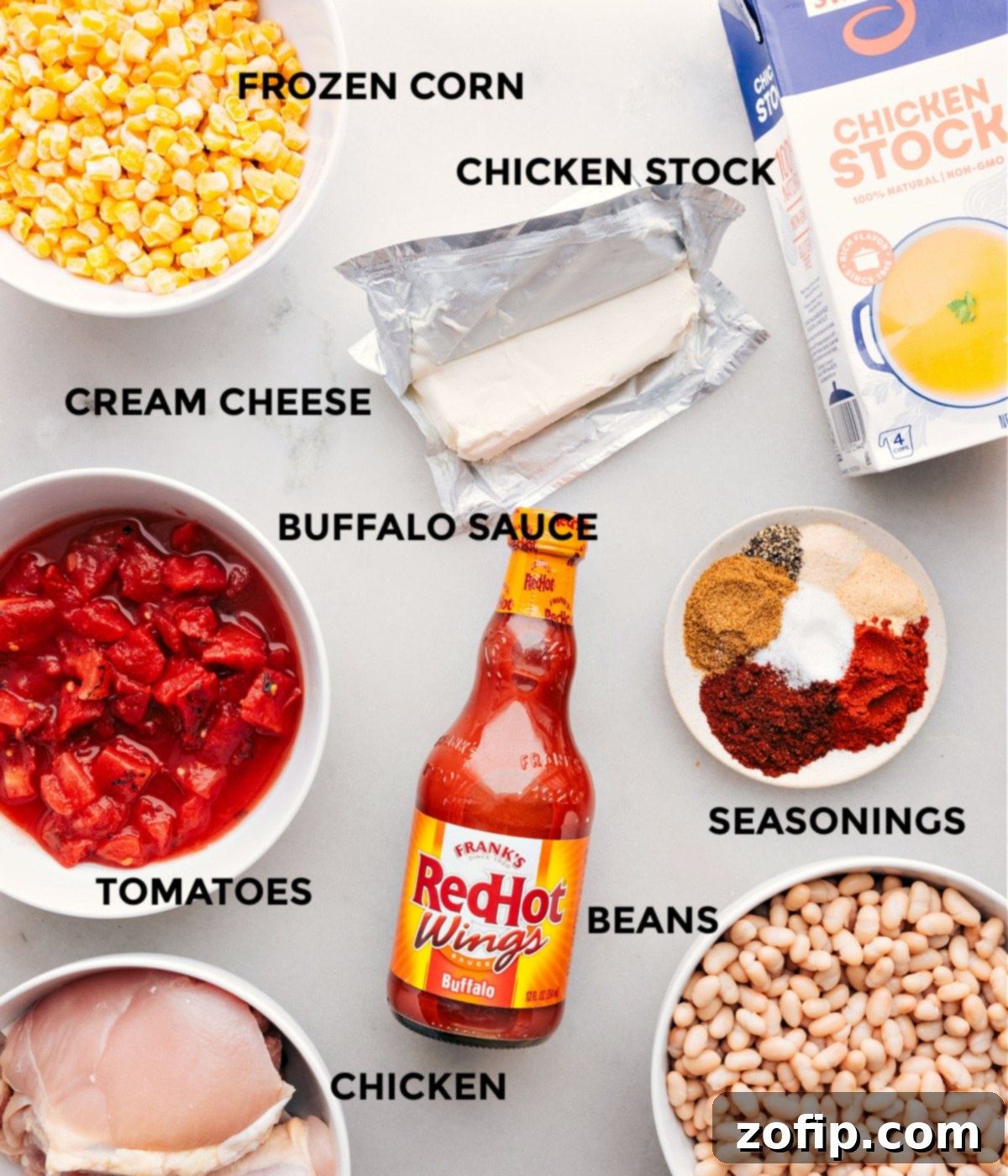 Ingredients used in this dish, including hot sauce, corn, beans, tomatoes, chicken stock, and chicken, neatly arranged.