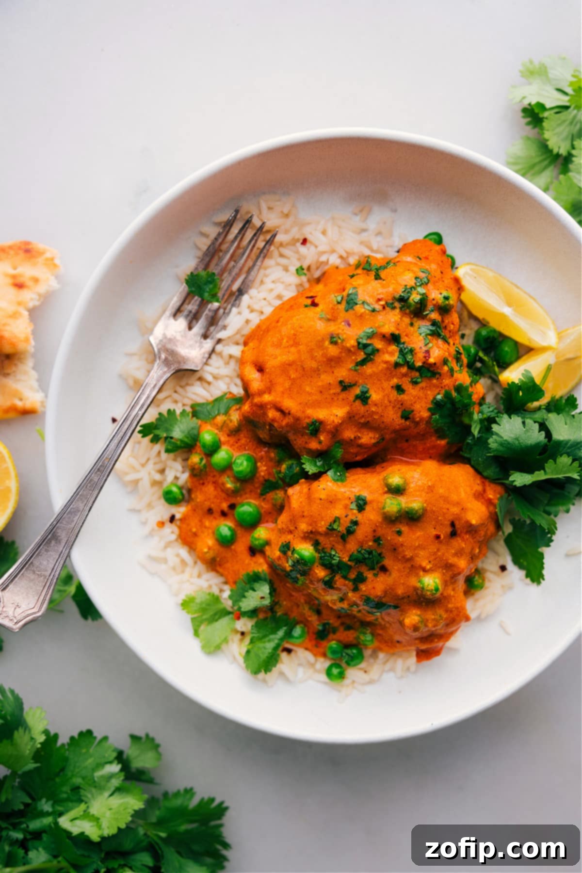 Delicious and Aromatic Chicken Tikka Masala Over Rice, Ready to Savor A beautifully presented, finished Chicken Tikka Masala dish, generously spooned over a bed of fluffy white rice, looking delicious, warm, and wonderfully aromatic.