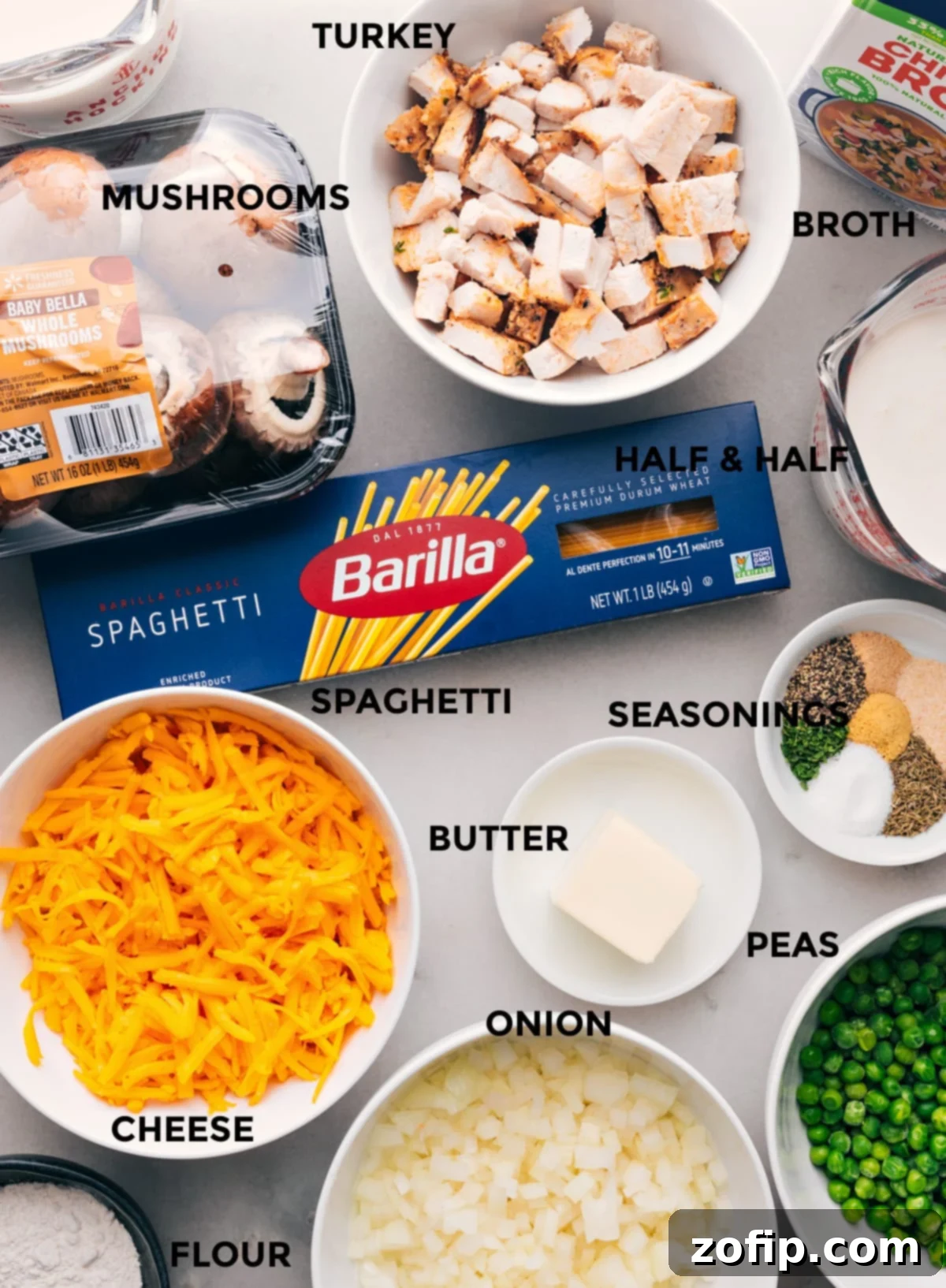 A collection of all the ingredients used in the recipe, including cheese, onion, peas, butter, noodles, and more.