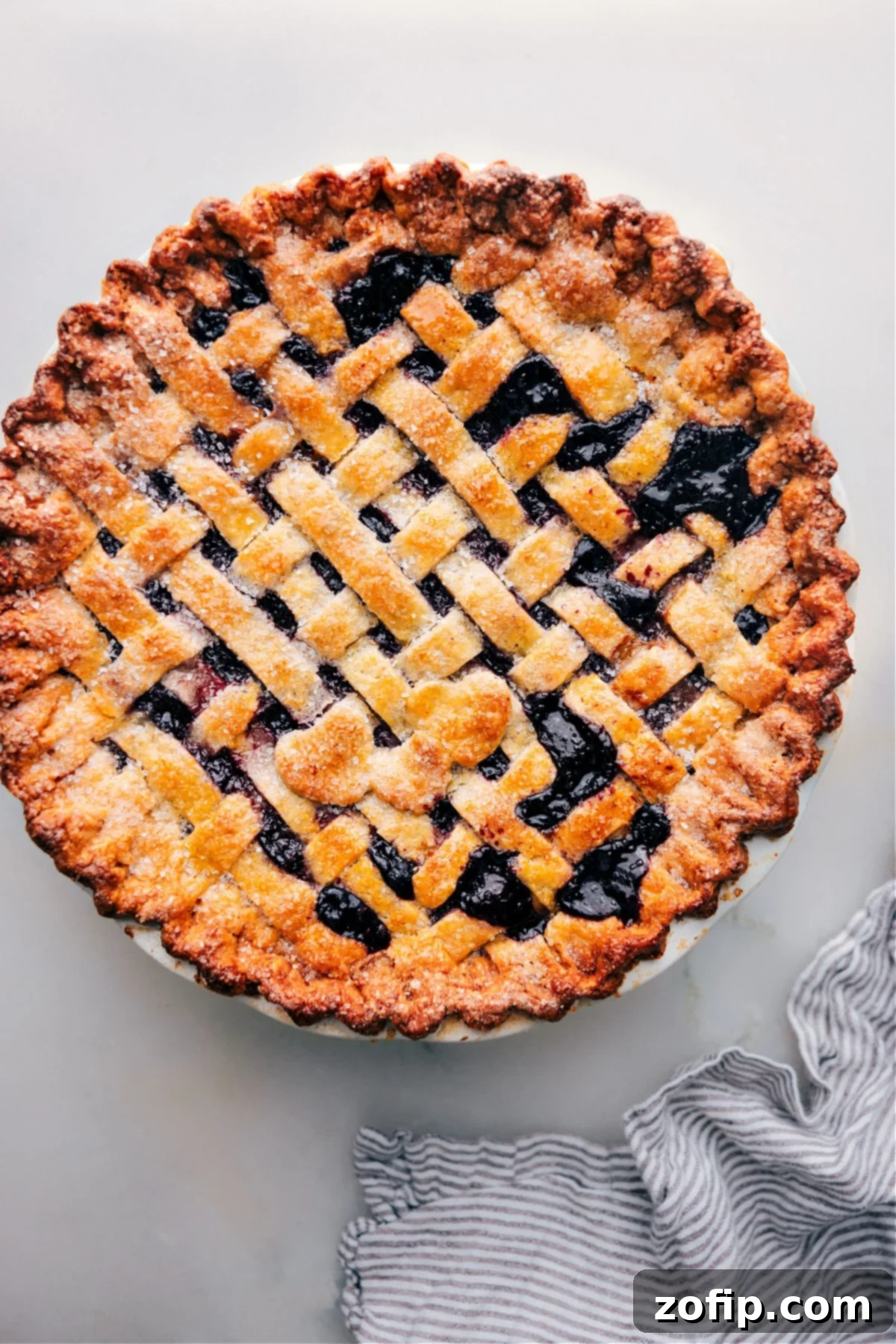 Thanksgiving Berry Pie Delicious baked Berry Pie ready to be sliced and enjoyed, with a golden-brown lattice crust and a scoop of vanilla ice cream melting on top.