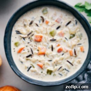 A steaming bowl of Creamy Chicken and Wild Rice Soup, garnished with fresh parsley, ready to be enjoyed as a comforting meal.