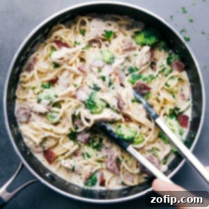 Chicken broccoli alfredo with tongs scooping up a creamy and delicious bite, ready to be enjoyed.