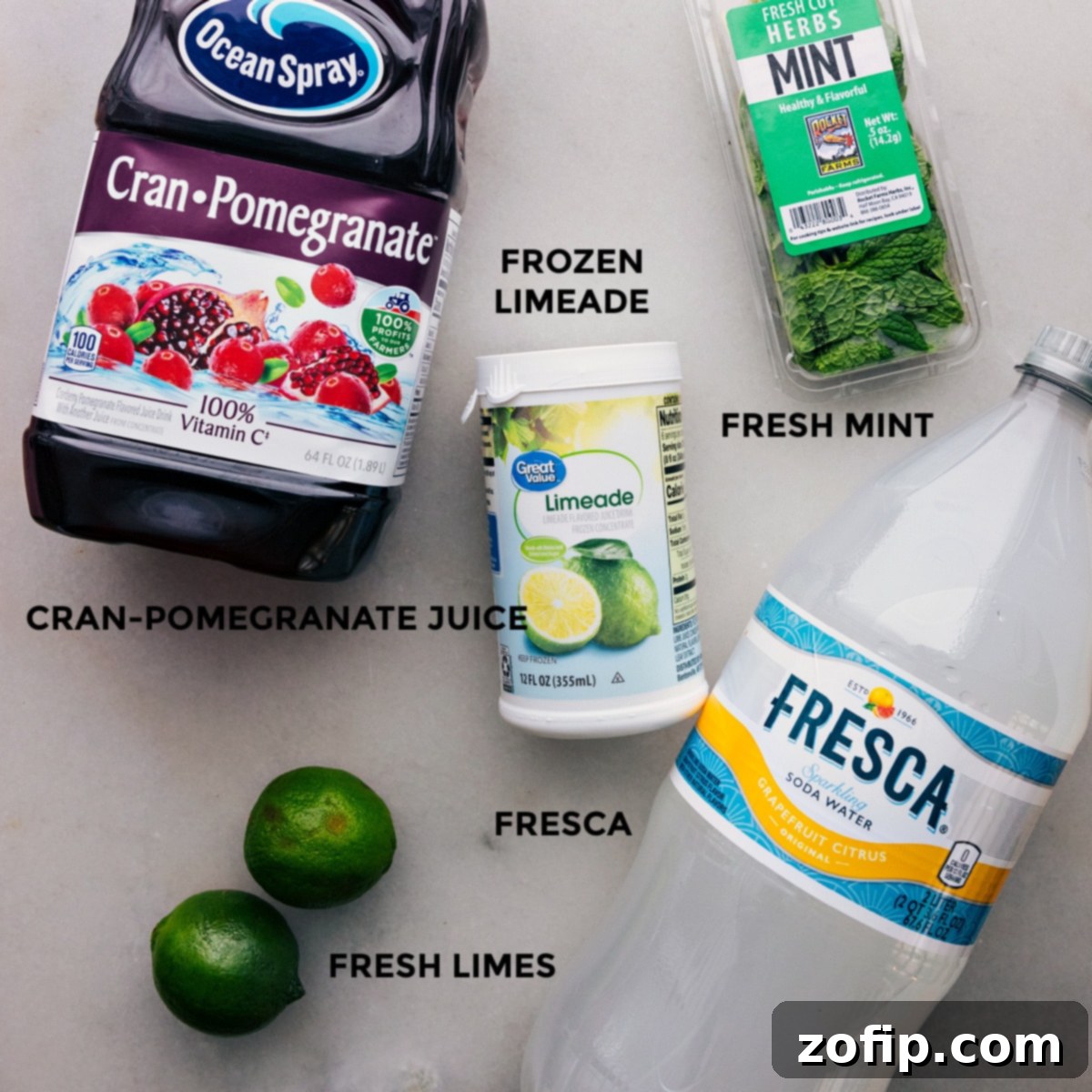 All the essential ingredients for Christmas punch—frozen limeade concentrate, a bottle of Fresca, cranberry-pomegranate juice, and fresh limes—neatly arranged on a surface, ready to be mixed into a delicious holiday beverage.