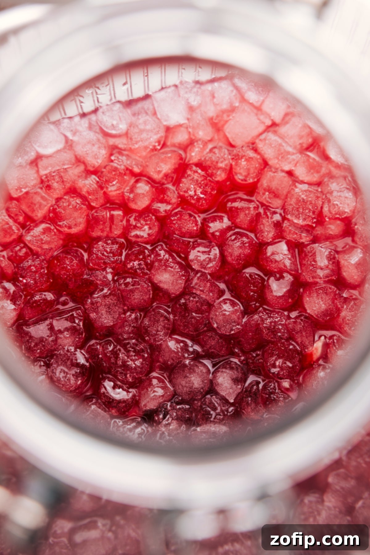 An overhead close-up shot of a single glass of Christmas Punch, filled with crushed ice, garnished with a fresh lime wedge and a sprig of mint, highlighting its refreshing appeal.