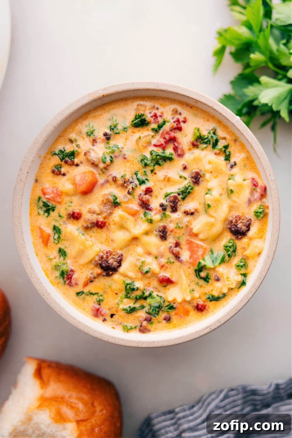 A steaming bowl of Creamy Italian Sausage Pasta Soup, garnished with fresh herbs and Parmesan.