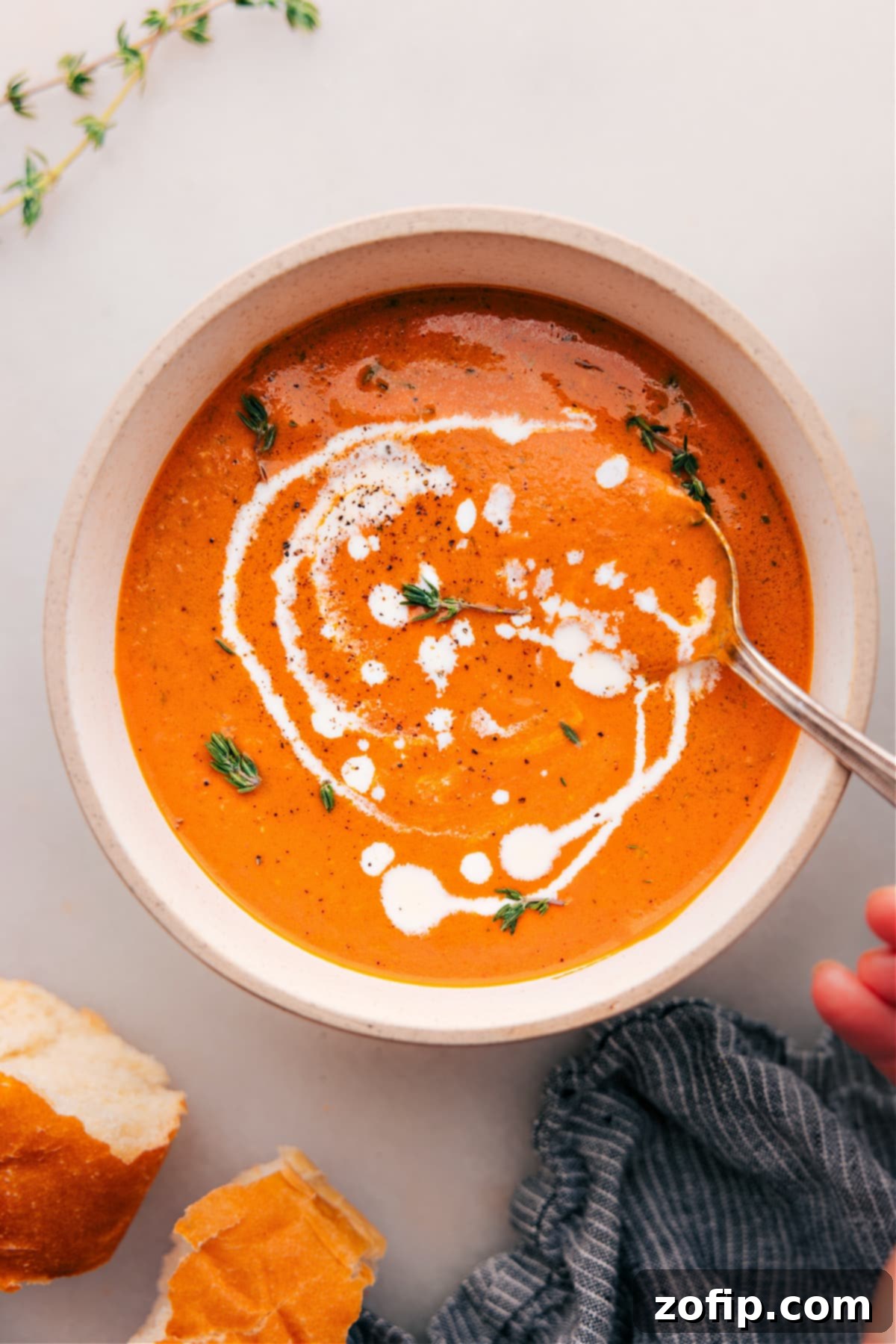 Creamy Roasted Red Pepper Soup Recipe A large bowl of creamy Roasted Red Pepper Soup garnished with fresh basil leaves and a swirl of vibrant green pesto, ready to be enjoyed.