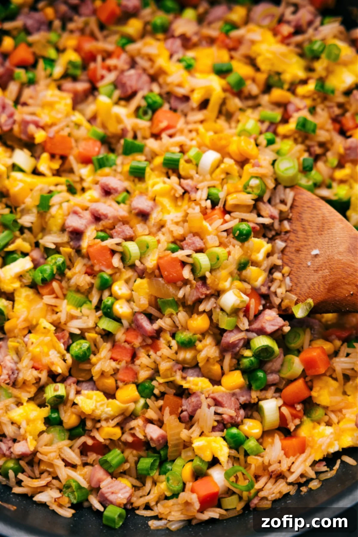 Everyones Favorite Ham Fried Rice A close-up shot of a spoonful of Ham Fried Rice, showcasing the tender ham, colorful vegetables, and perfectly coated rice, ready to be enjoyed.