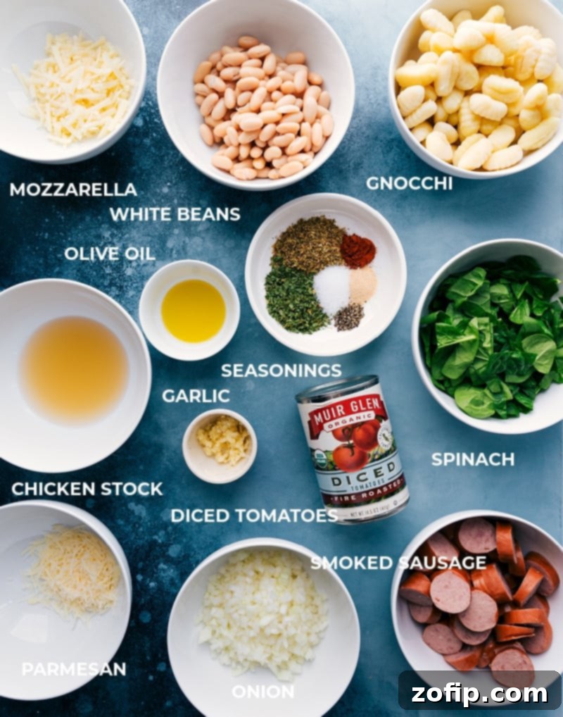 Ingredients laid out for a delicious One-Skillet White Bean Gnocchi with smoked sausage, fire-roasted tomatoes, and spinach. #recipeingredients #easycooking #comfortfood A flat lay photograph showcasing all the fresh and pantry ingredients needed for making White Bean Gnocchi, including gnocchi, sausage, beans, tomatoes, and spices.