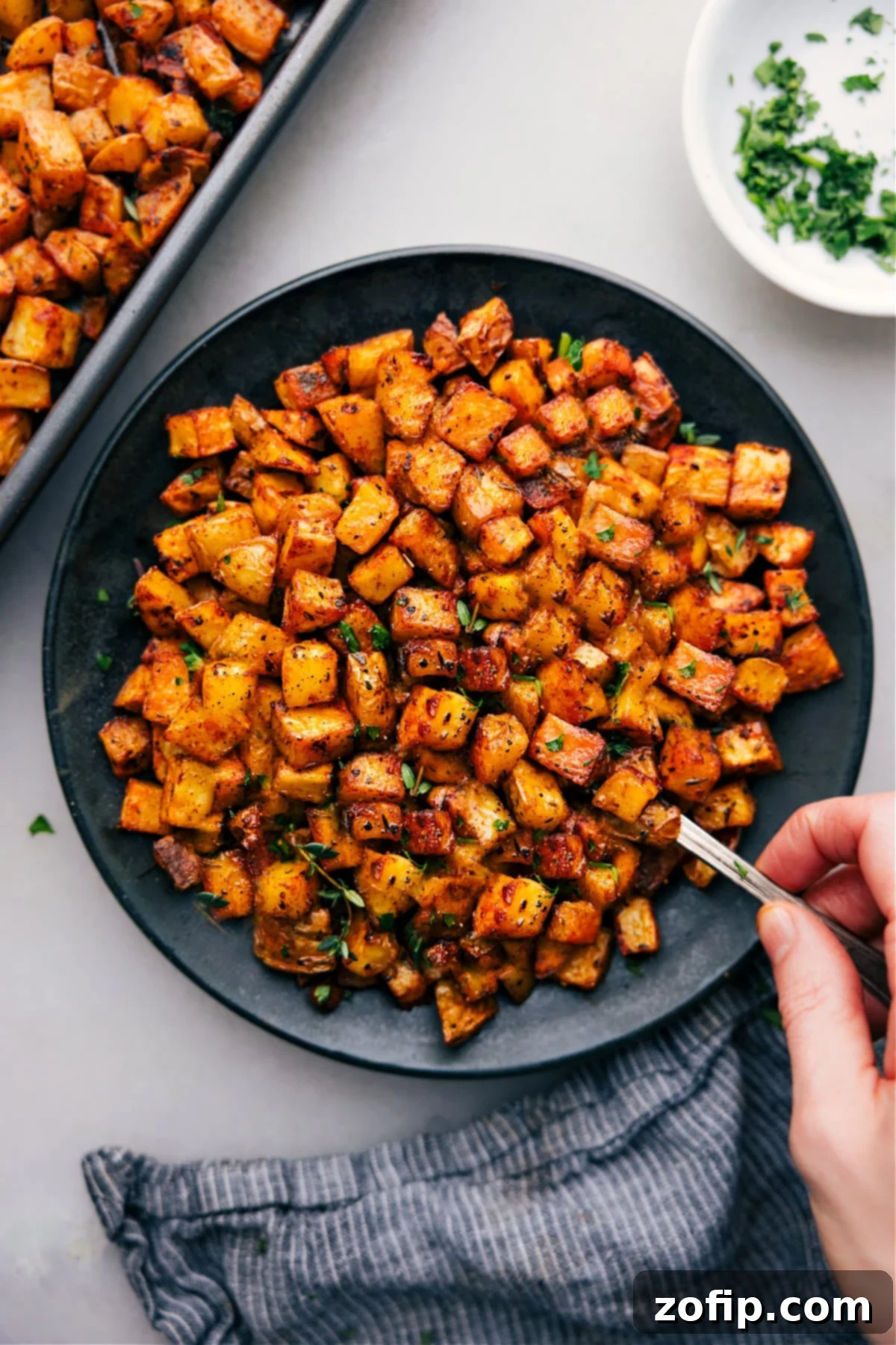 A large plate full of irresistible crispy breakfast potatoes, garnished with fresh herbs, ready to be devoured.