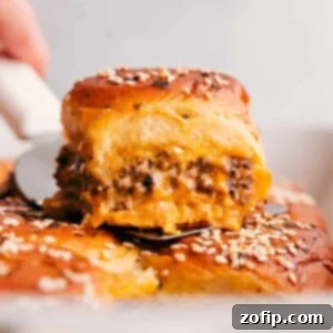 Cheeseburger sliders fresh out of the oven, golden and cheesy, garnished with sesame seeds.
