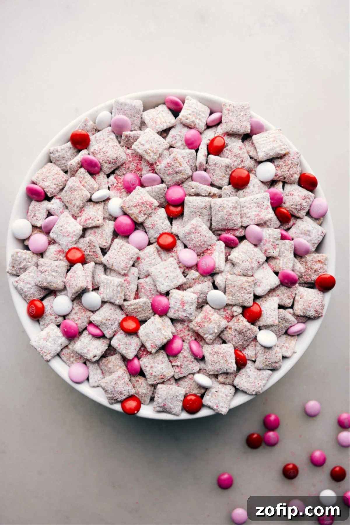 Delicious Valentine Muddy Buddies for a Festive Treat A large bowl brimming with festive Valentine Muddy Buddies, showcasing the colorful M&M's and powdered sugar coating.