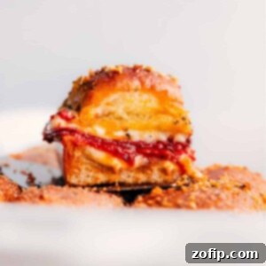 Cheesy Pull-Apart Pizza Sliders 2 Close-up of a single pizza slider showing the melted cheese and pepperoni inside, cut to reveal layers.