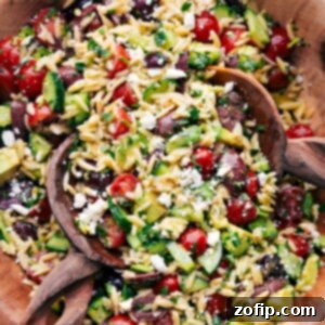 Wooden spoons, tossing a batch of Mediterranean Orzo Salad.