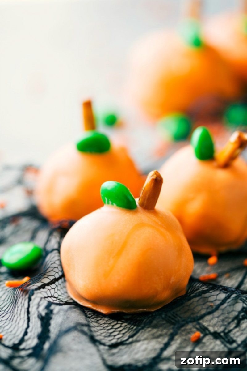 Spooky Oreo Truffles 3 Festive Pumpkin Oreo Balls: A vibrant orange truffle adorned with green M&M's and pretzel stems, perfect for Halloween celebrations.
