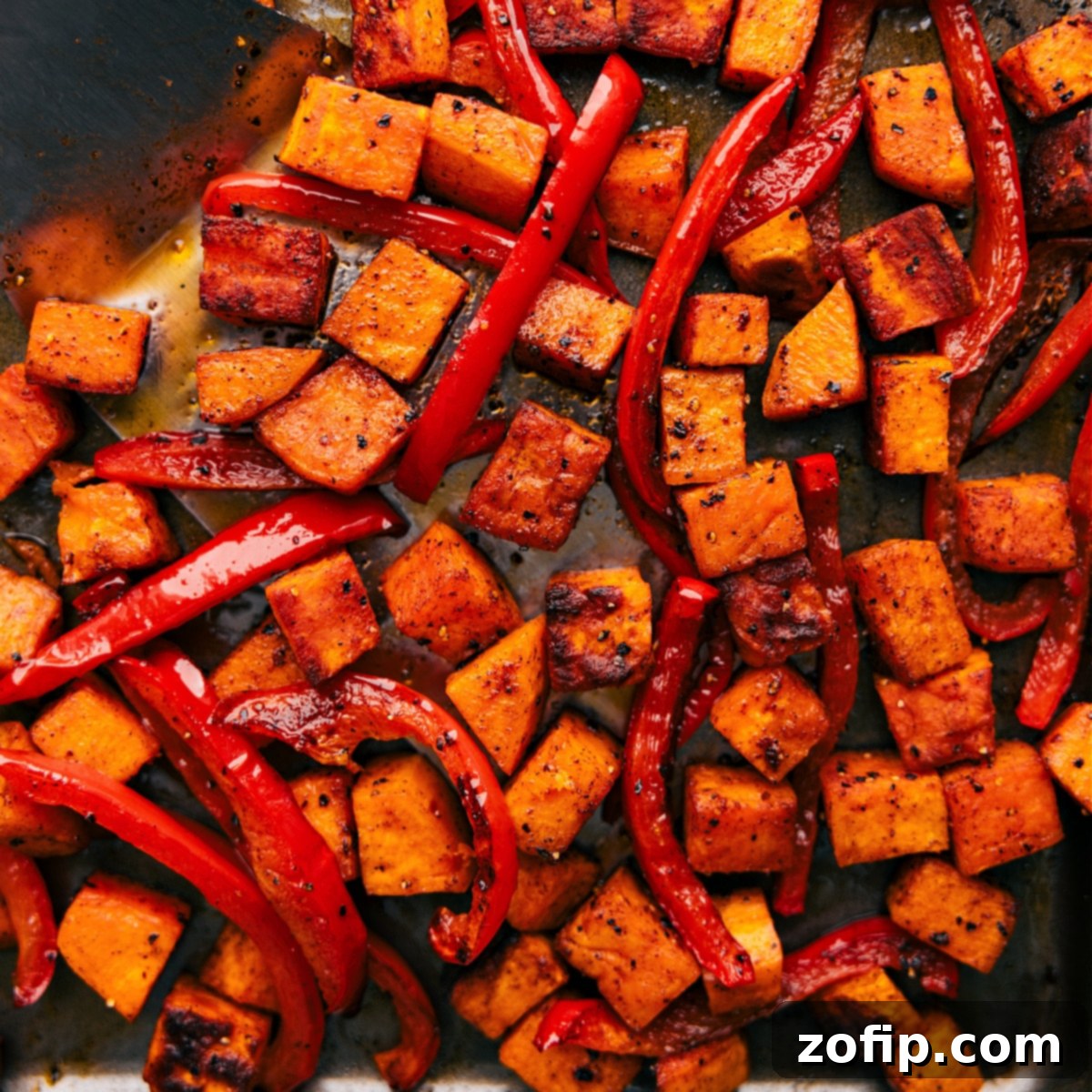 Tray of freshly roasted potatoes and peppers, golden brown and sizzling straight out of the oven.
