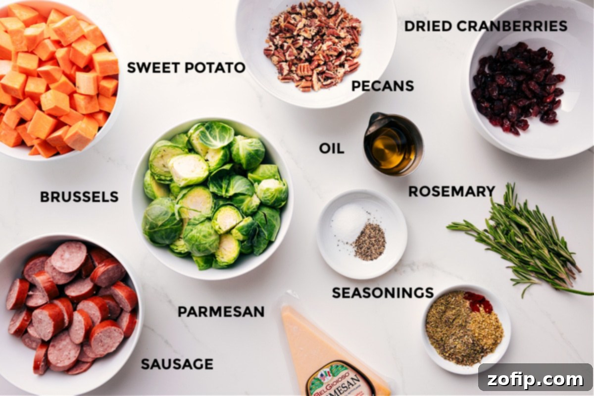 Carefully prepped ingredients arranged for a sheet pan dinner: diced sweet potatoes, sliced sausage, trimmed Brussels sprouts, fresh rosemary sprigs, dried cranberries, chopped pecans, and grated Parmesan cheese.