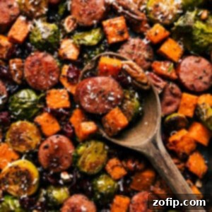 A serving of Harvest Vegetables and Sausage on a plate, garnished with fresh rosemary and cranberries.
