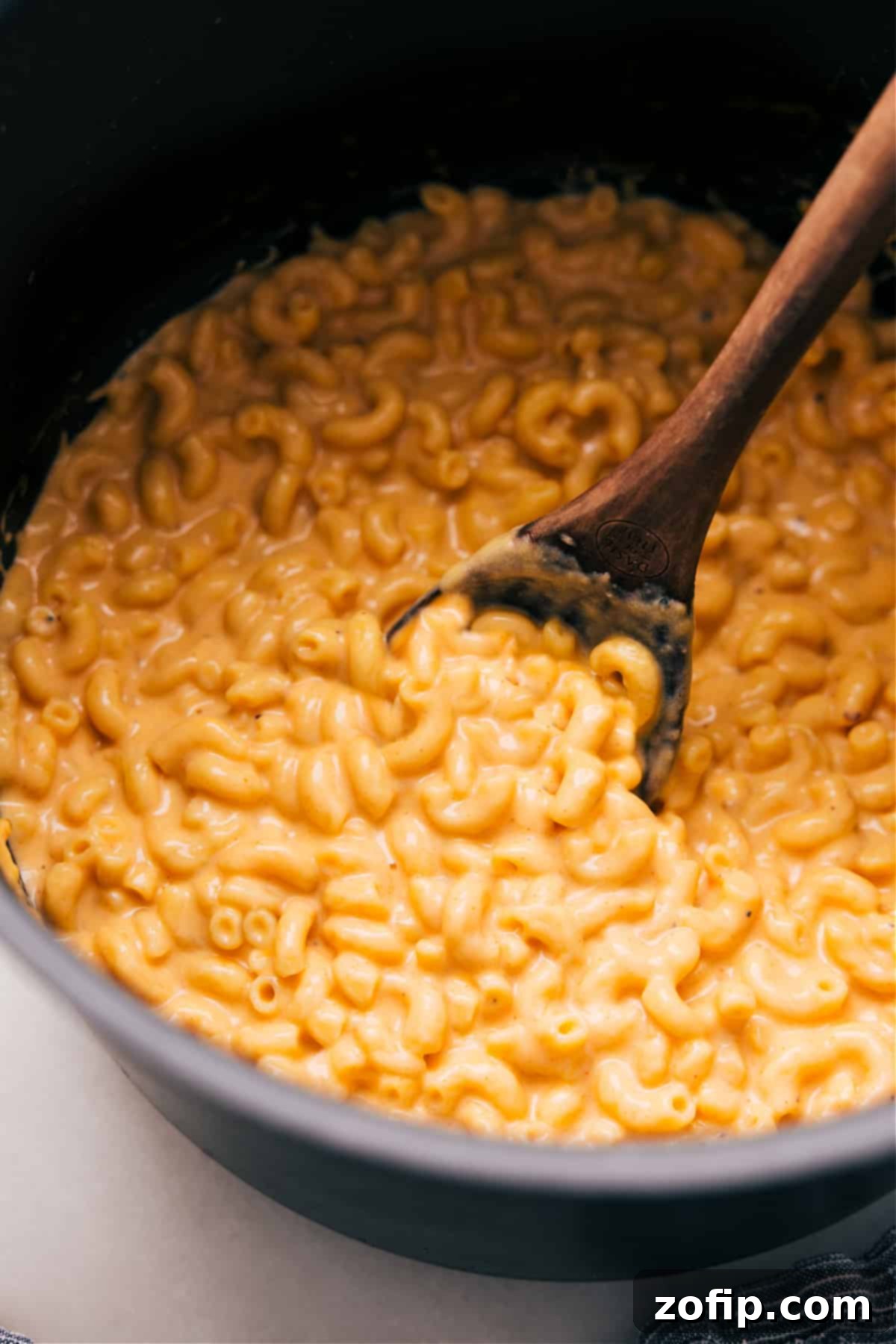 A delicious serving of creamy Mac and Cheese being scooped from a large pot, showcasing its rich texture and golden color.