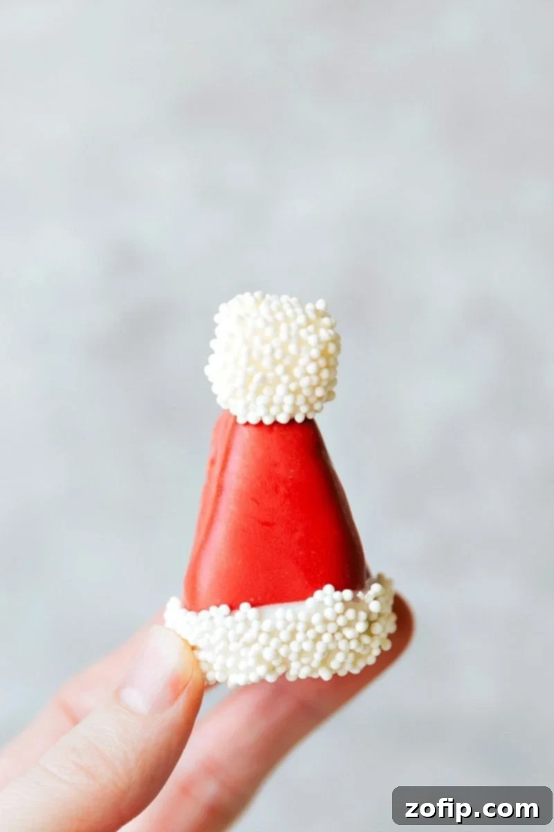 Five different ways to dress up an OREO Cookie truffle for Christmas — Santa's hat, Reindeer, Ornament, Snowman, and Christmas hearts. These easy and delicious Christmas OREO Cookie truffles are perfect for a party, to gift to neighbors, bring into work, or enjoy with your family! Recipe via chelseasmessyapron #holidays #best #quick #easy #five #christmas #oreo #truffles Image of the Santa hat Oreo truffle, showcasing one of five Christmas Oreo cookie truffles