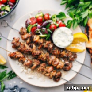 Vibrant Greek Chicken Bowls 2 Greek Chicken Bowls on a plate with an easy greek salad, tzatziki dressing, all over rice.