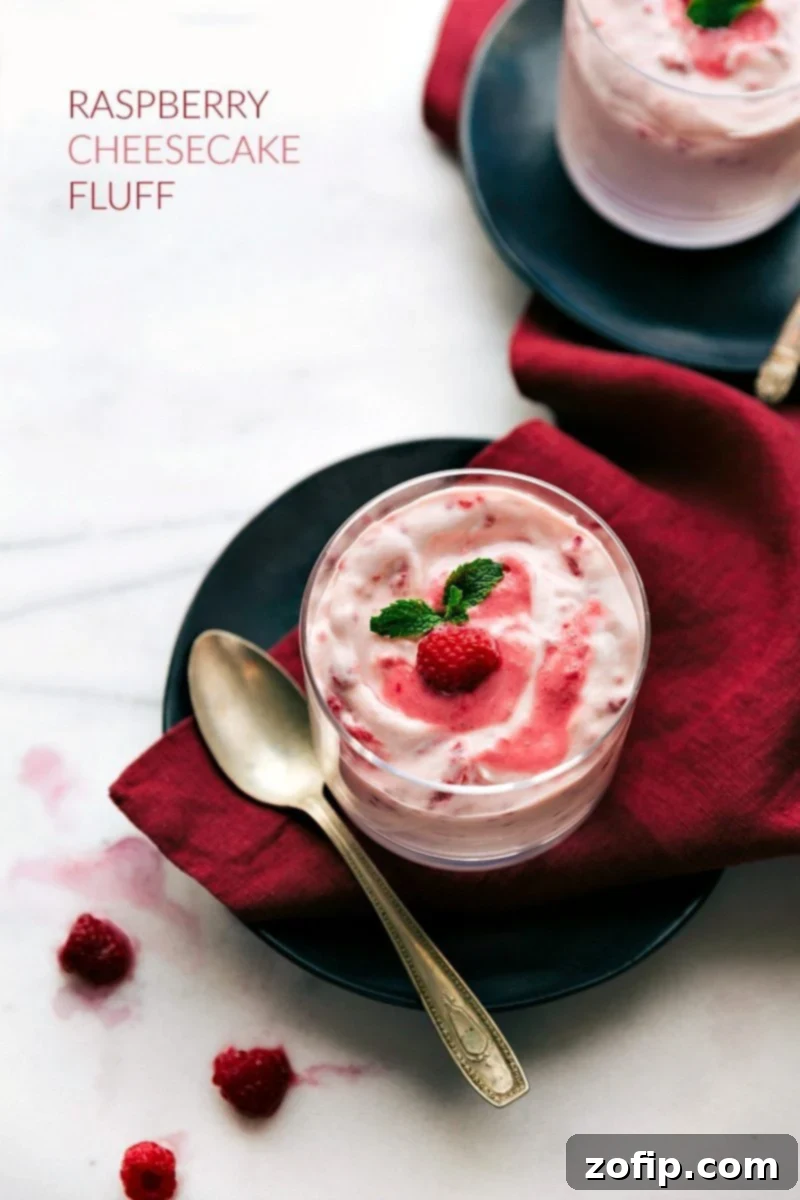 A beautiful overhead shot of creamy raspberry fluff served in a clear glass cup, garnished with a fresh raspberry, ready to be enjoyed as a light dessert or a refreshing side dish.