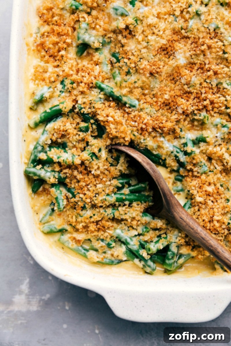 Ready-to-eat green bean casserole in a pan, showcasing its crisp top and a serving spoon, ready for a holiday meal.
