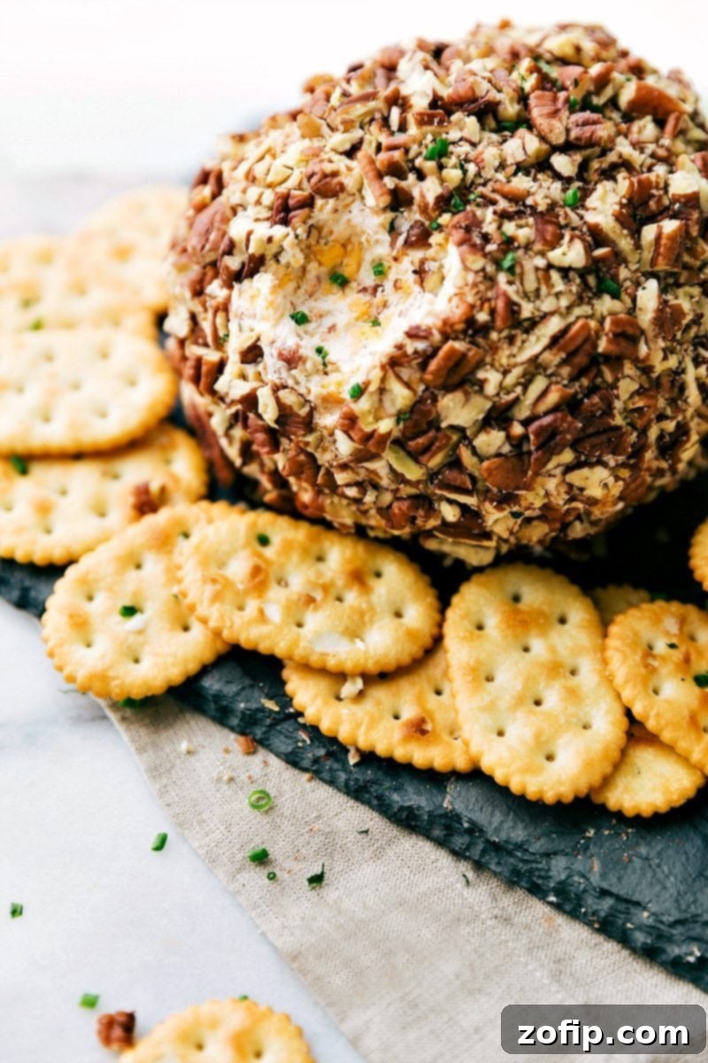 A gorgeous cheese ball with crackers on the side, and a bite scooped out of it, ready to be enjoyed as both a delicious and visually appealing snack.
