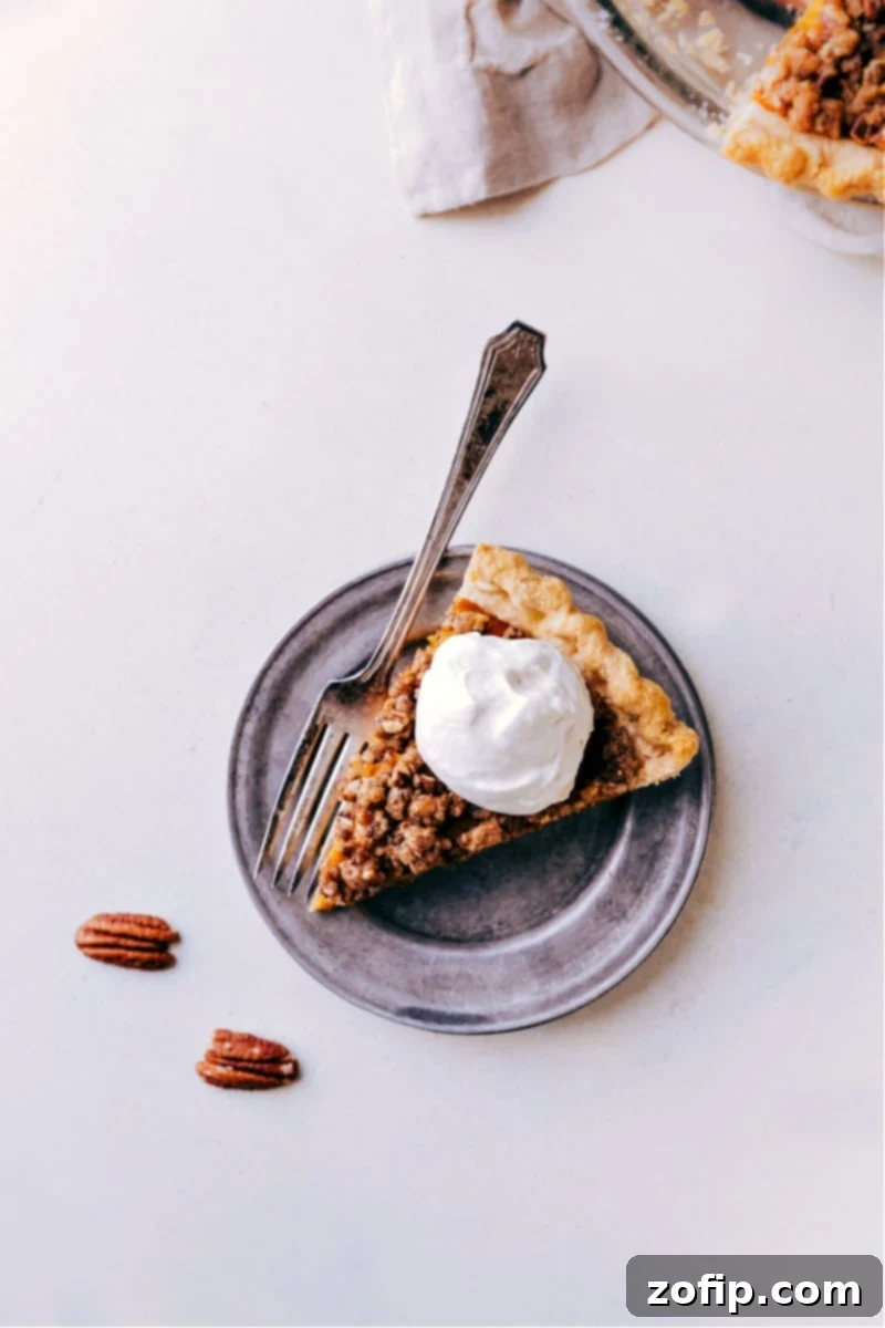 A delectable slice of Pumpkin Pecan Pie, perfectly baked and topped with a generous dollop of maple whipped cream, showcasing its rich layers and inviting texture. Ideal for Thanksgiving and holiday celebrations.