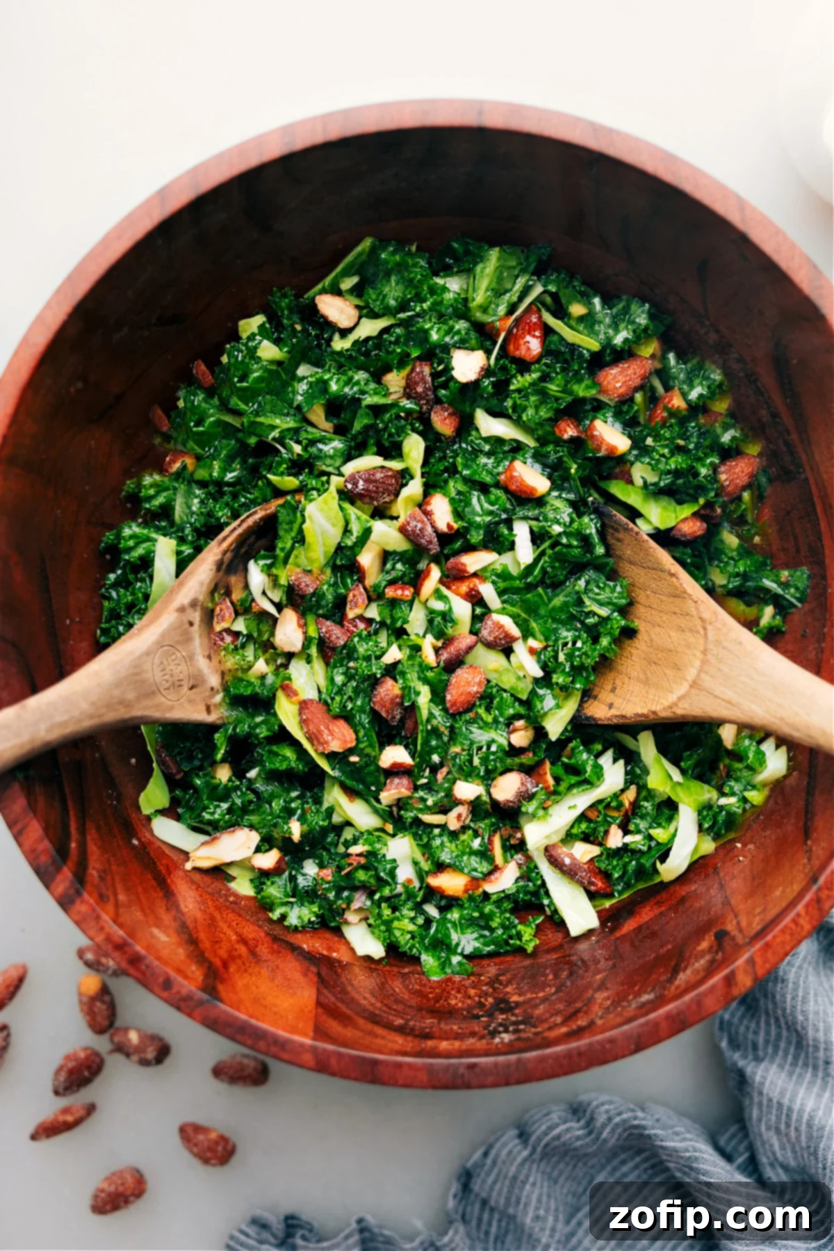 A vibrant Chick-fil-A Kale Crunch Salad copycat in a large wooden bowl, perfectly tossed and ready to be served. Highlights crisp greens, golden almonds, and a creamy dressing.