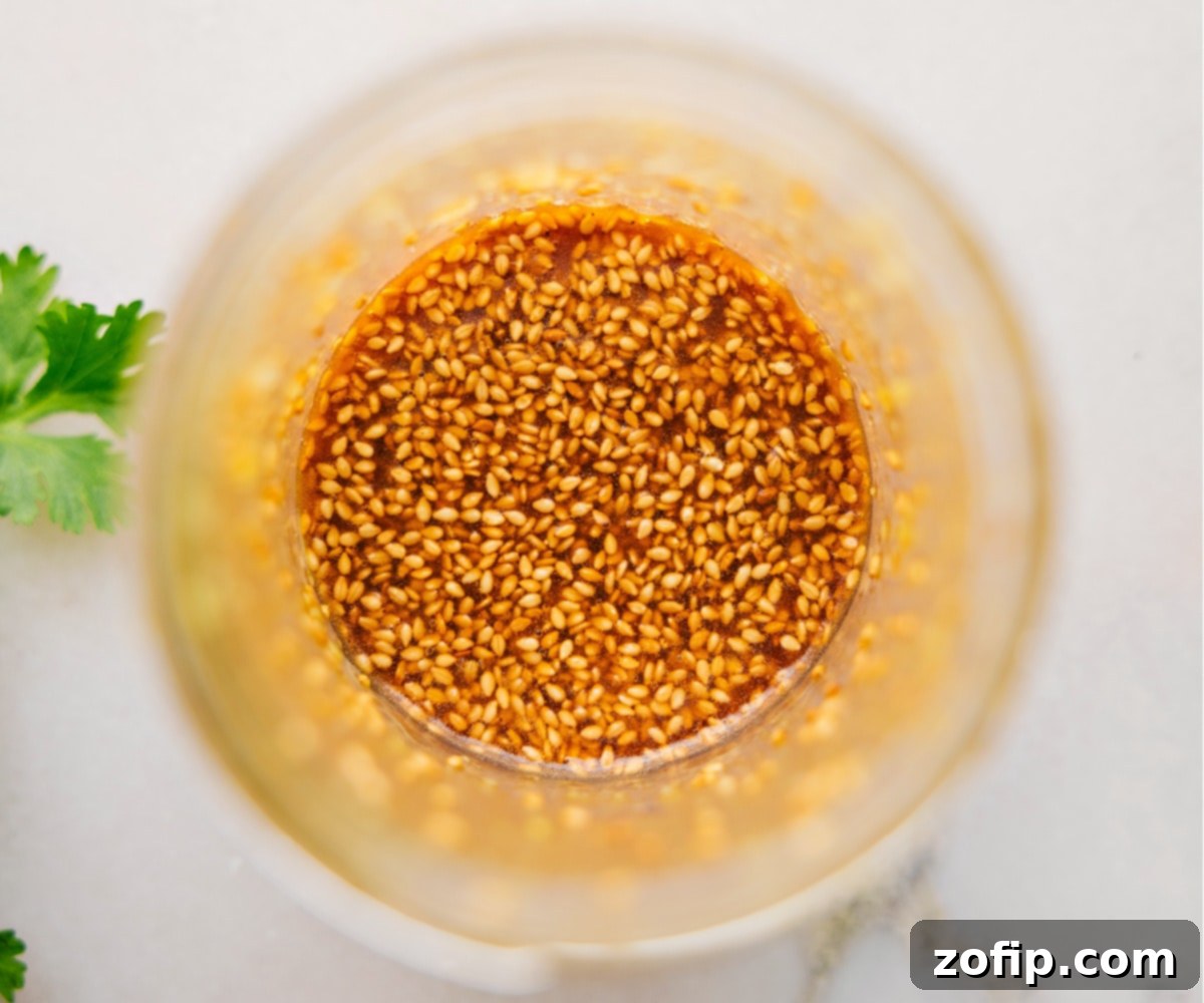 The Zesty, Savory Dressing for Smashed Cucumber Salad The perfectly mixed Smashed Cucumber Salad dressing in a clear mason jar, highlighting its vibrant color and readiness for use.