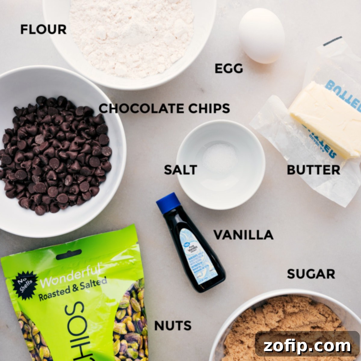 All essential ingredients for the blondie recipe neatly laid out: flour, salt, butter, vanilla bean paste, brown sugar, an egg, and a selection of pistachios and chocolate chips.