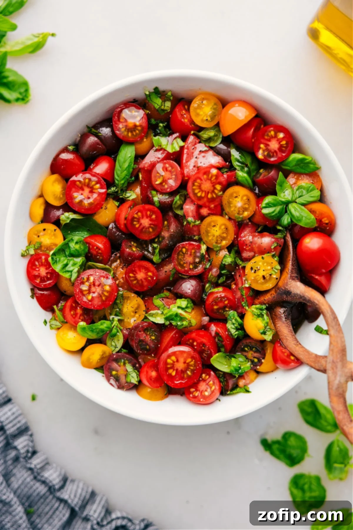 A beautiful bowl of fresh tomato salad, garnished with vibrant green basil leaves.