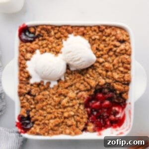 Cherry crisp in a pan with a scoop removed, revealing its delectable contents.