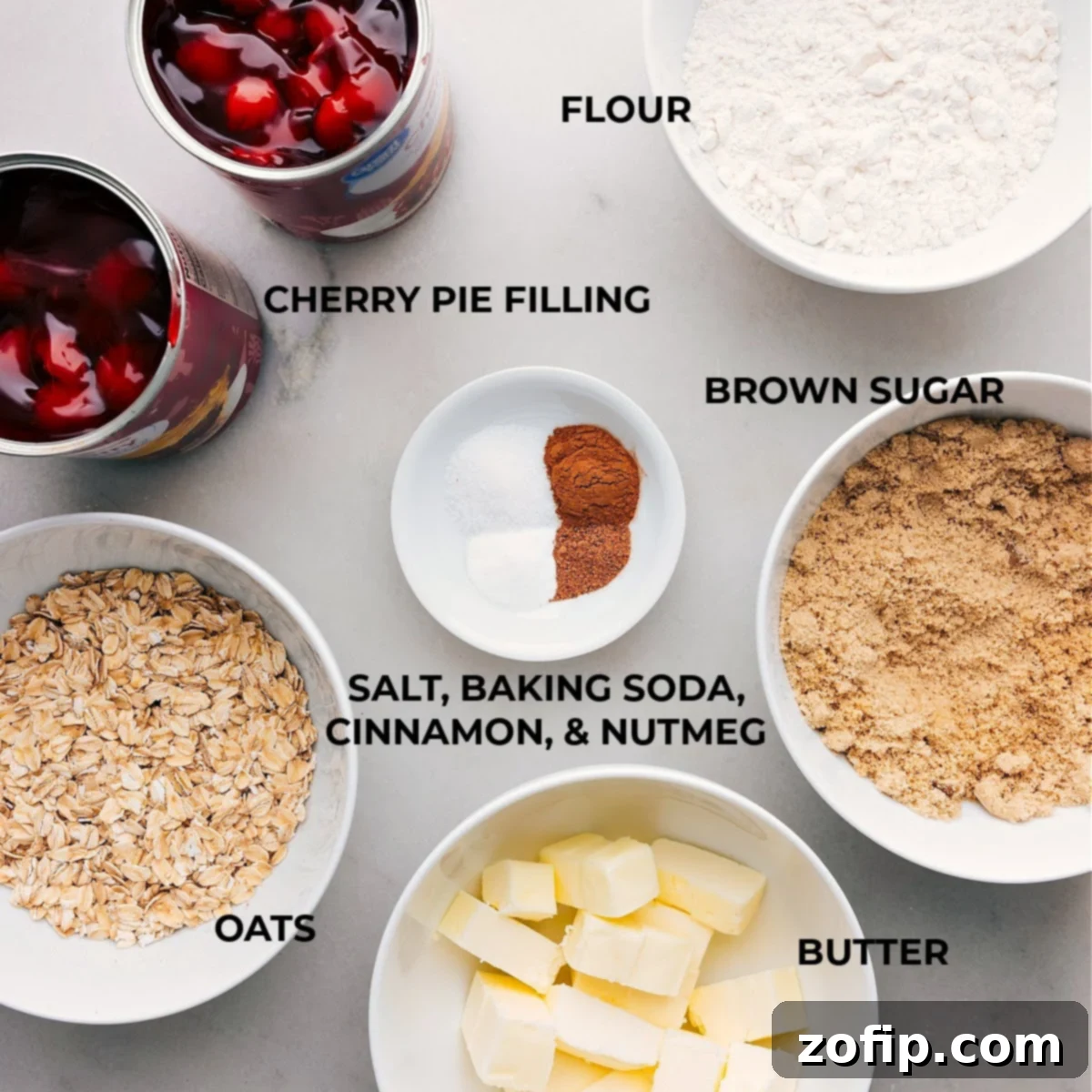 A flat lay of fresh cherries, old-fashioned oats, brown sugar, flour, butter, and spices—all the essential ingredients for a homemade cherry crisp.