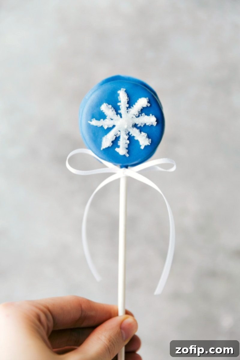 Image of a beautiful Snowflake Oreo Pop, adorned with white decorating gel and sparkling sugar.