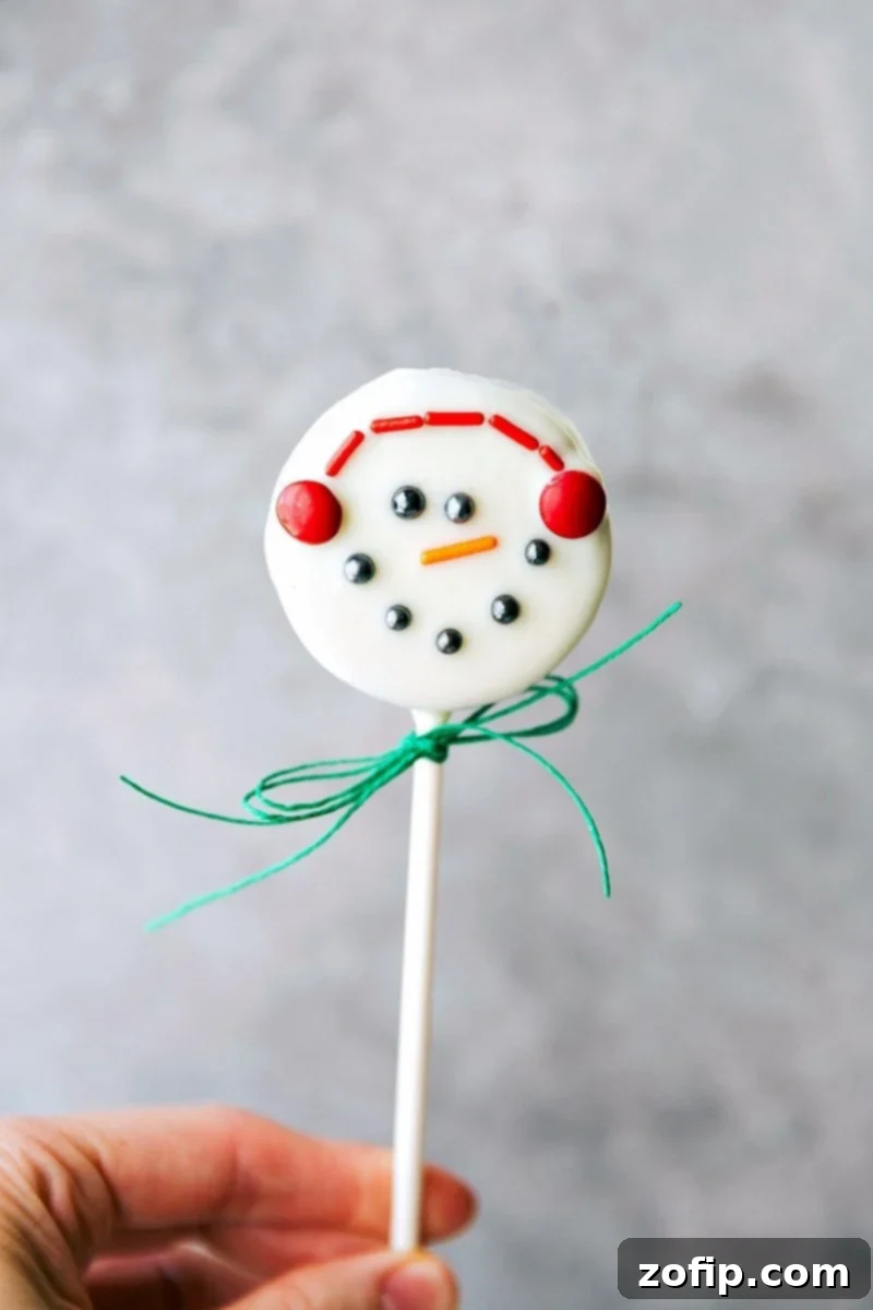 Snowman Oreo Pop: a delightful Christmas treat Close-up image of an adorable Snowman Oreo Pop, complete with earmuffs and a carrot nose.