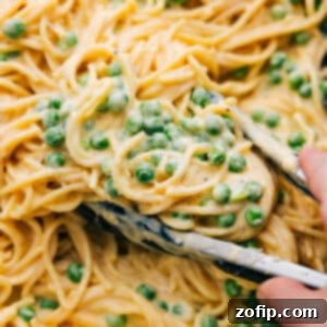 Ultimate Cheesy Spaghetti 2 A close-up of a serving of Cheesy Spaghetti with peas in a bowl, ready to be eaten.