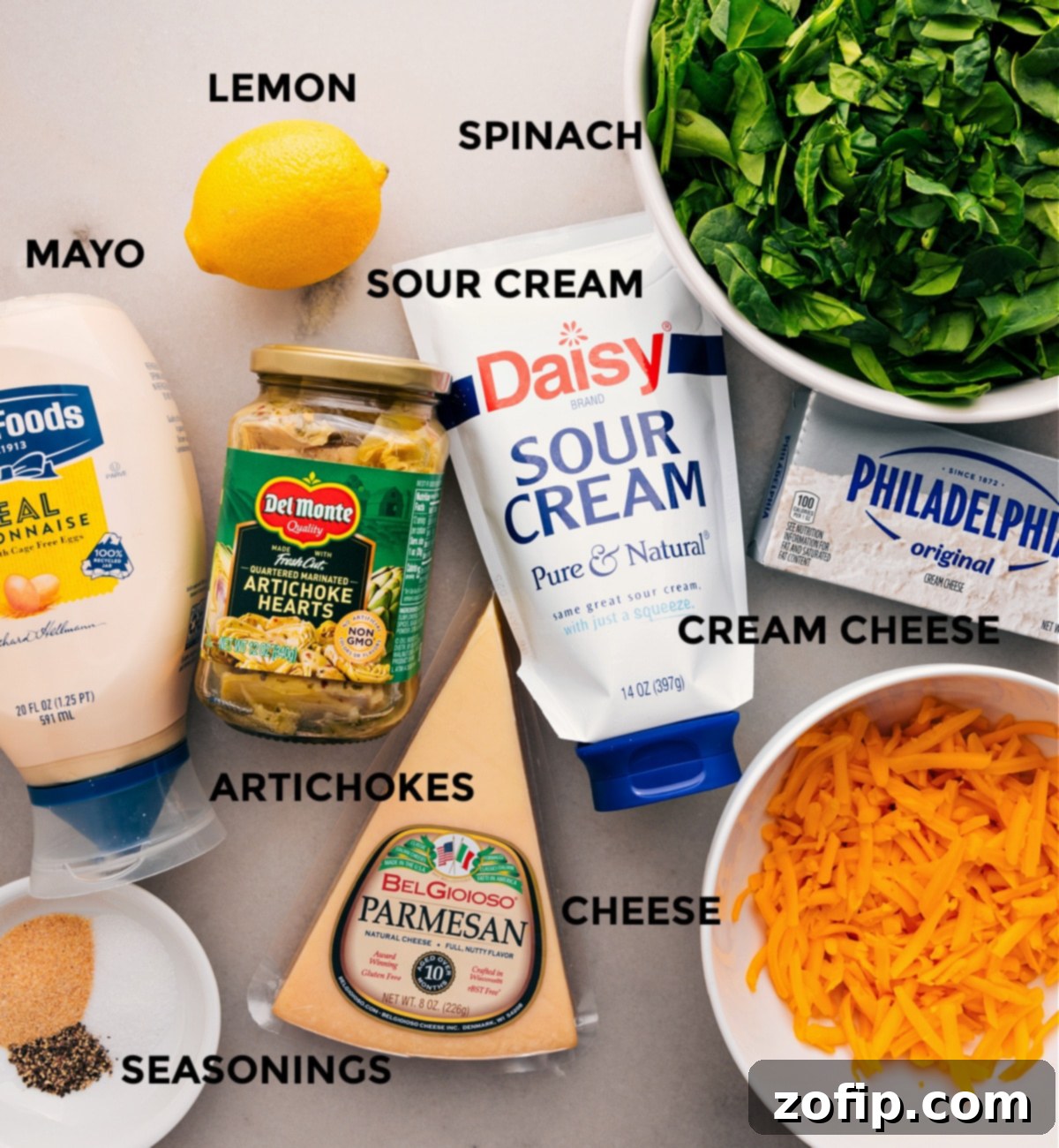 All the fresh ingredients for this recipe, including spinach, artichokes, cream cheese, mayo, and various cheeses, are prepped and neatly arranged for easy assembly.