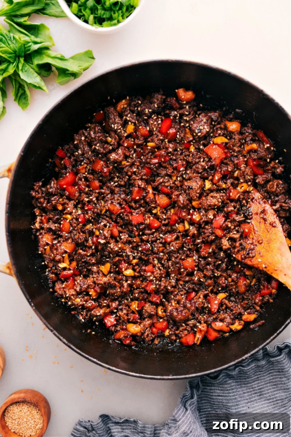 A pot of delicious Asian Ground Beef, garnished with sesame seeds and fresh green onions, ready to be served.