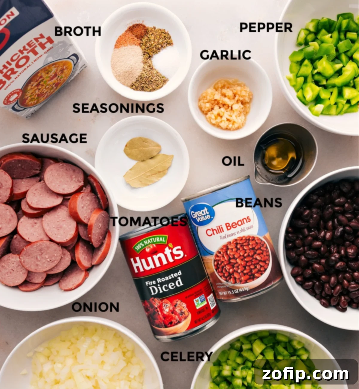 All the ingredients for this recipe are prepped and ready for easy assembly: meat, broth, seasonings, peppers, oil, beans, and tomatoes.