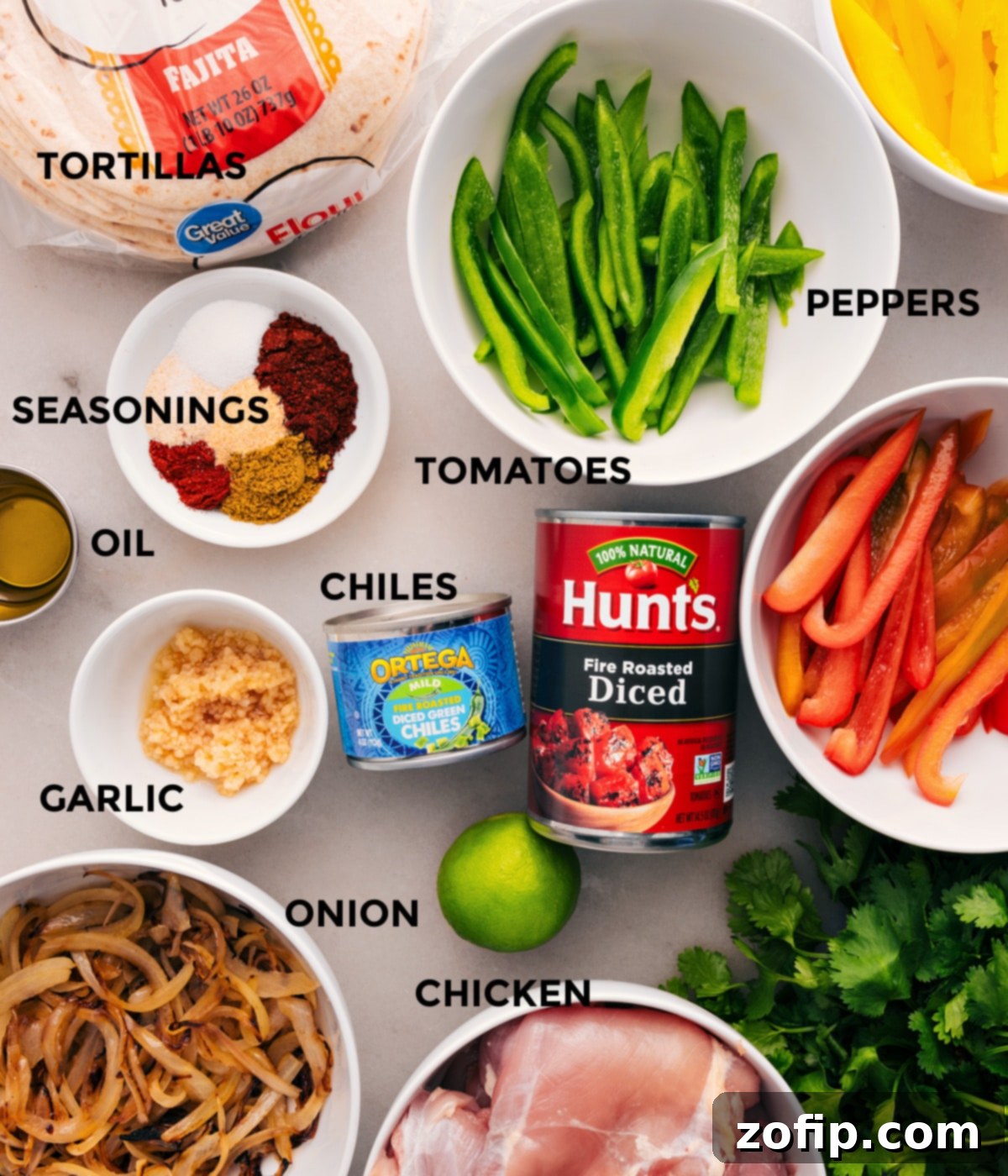 A vibrant array of fresh ingredients for Crockpot Chicken Fajitas laid out: bell peppers, chicken thighs, diced tomatoes, green chiles, garlic, seasonings, tortillas, onions, and limes.