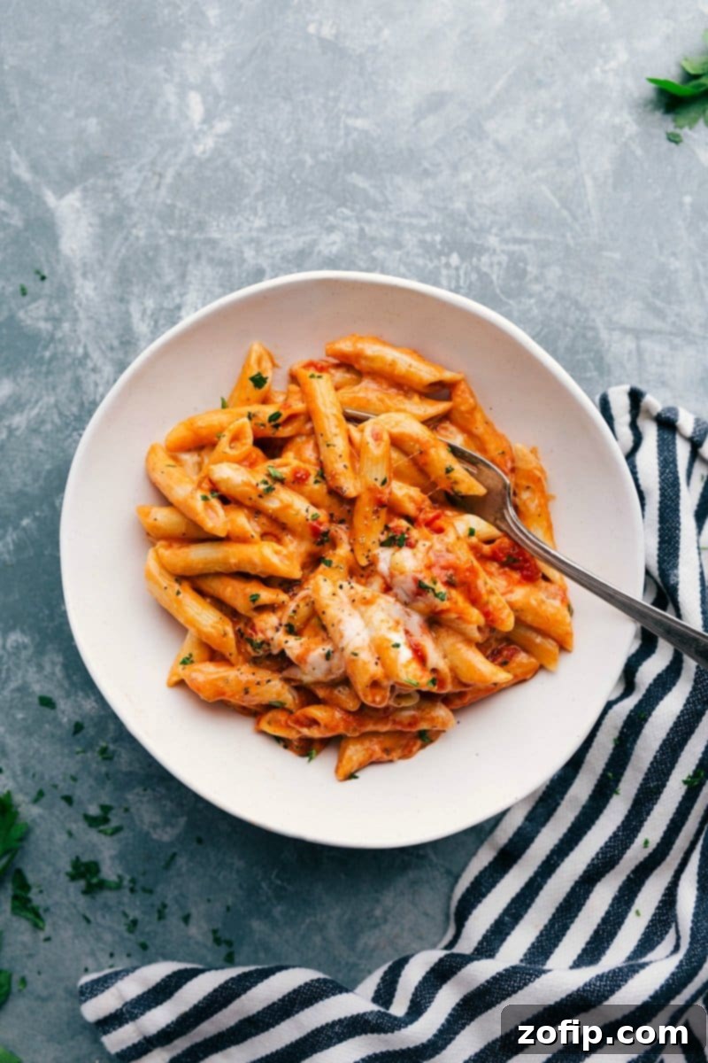Red and White Pasta Topped with Fresh Cheese - A Warm and Appetizing Dish Warm and delicious red and white pasta in a bowl, complete with a fork and topped with freshly shredded cheese.