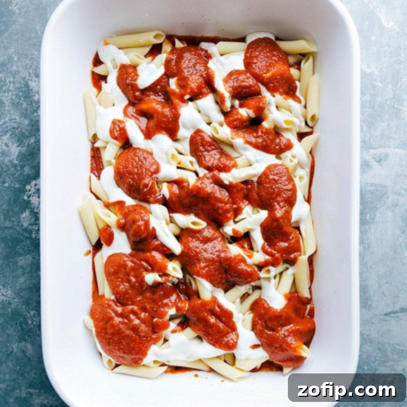 Layering Marinara Sauce Over Alfredo - A Signature Element of the Red and White Pasta Marinara sauce being layered on top of alfredo sauce in a pasta dish, creating a rich flavor combination.