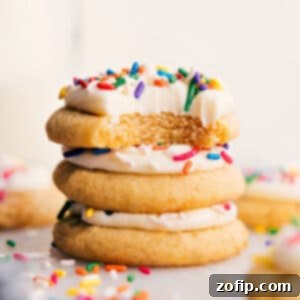 A close-up shot of a stack of freshly baked soft sugar cookies with generous cream cheese frosting and colorful sprinkles.